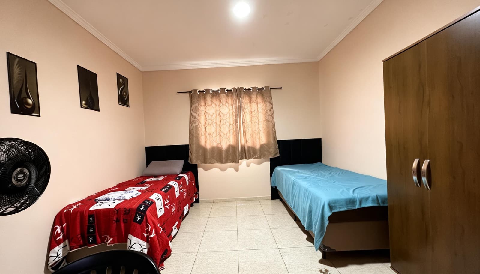 Quarto com duas camas, armário, cortina e espaço central de circulação.