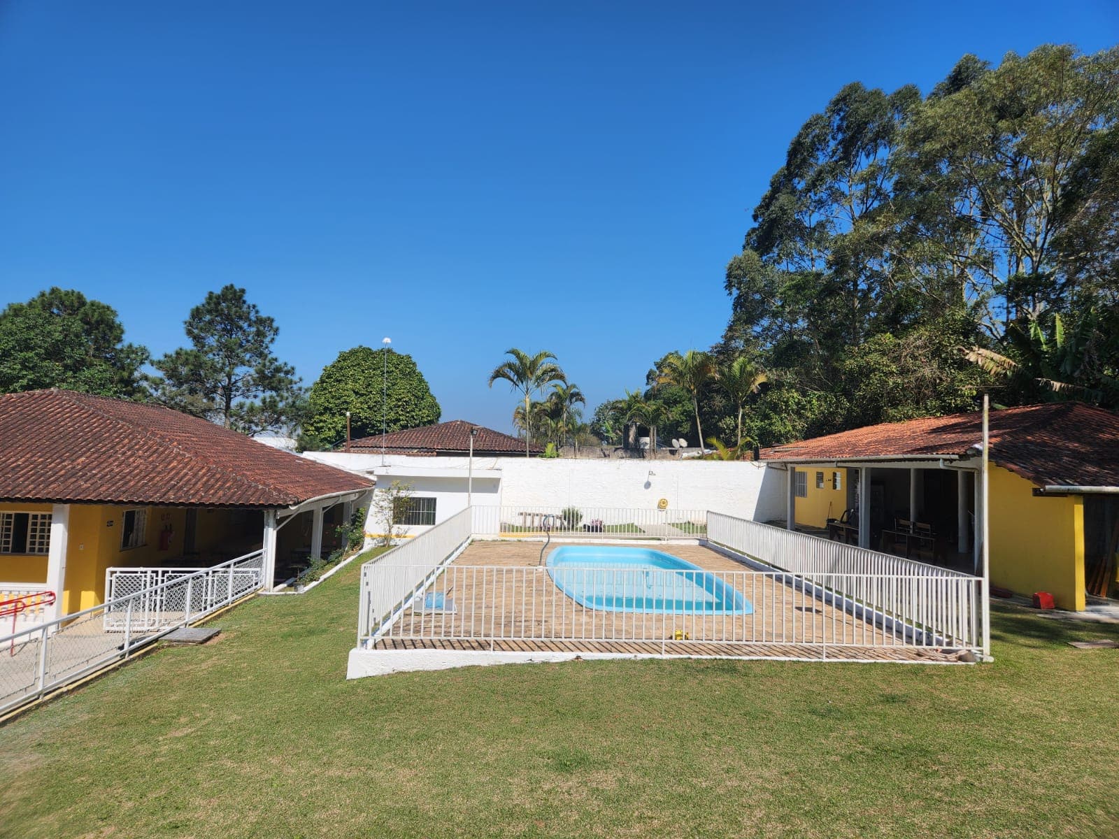 Piscina cercada entre construções e gramado na propriedade da Arhat.