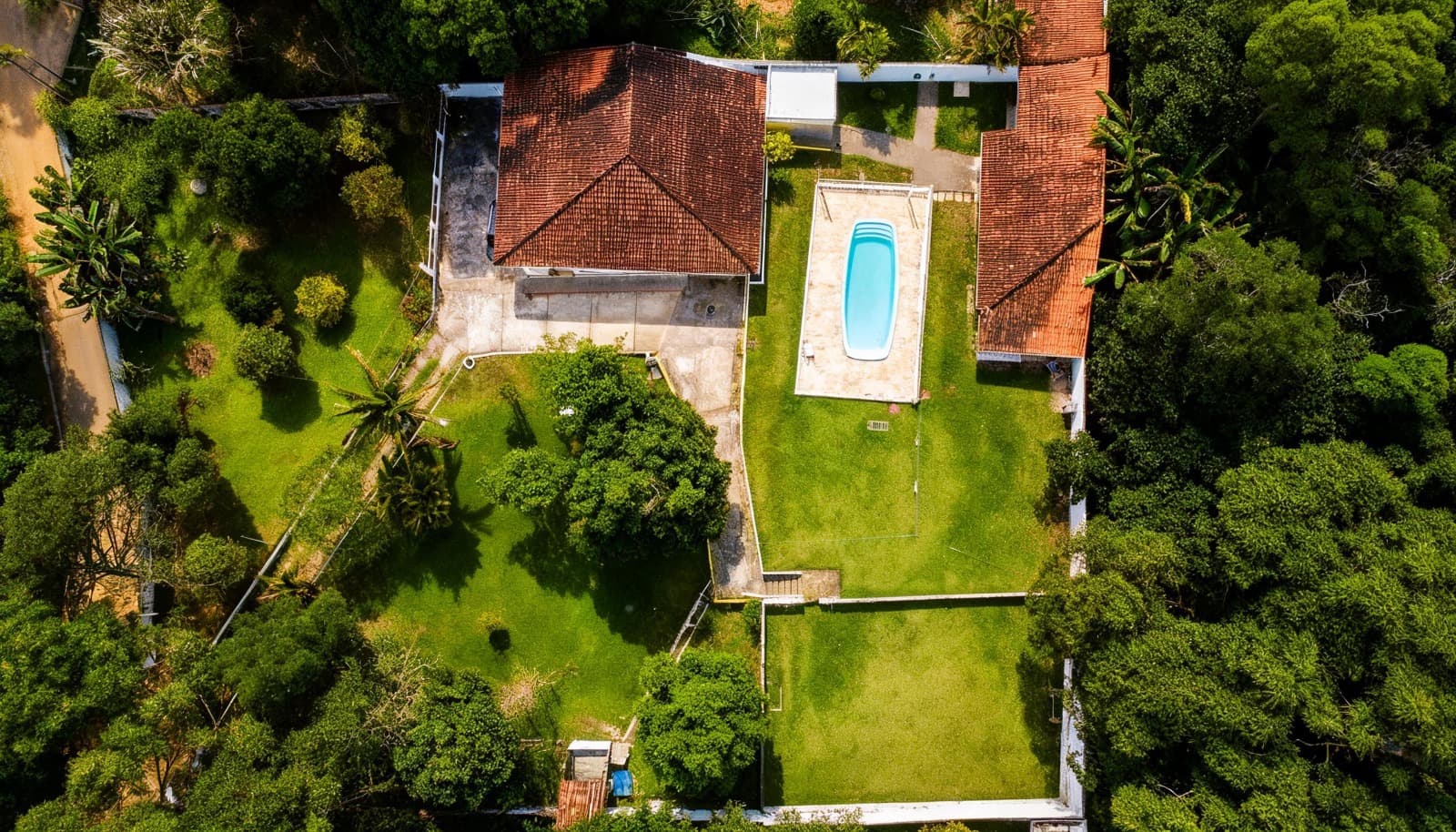 Vista aérea superior da propriedade Arhat, com construções, piscina e áreas verdes.
