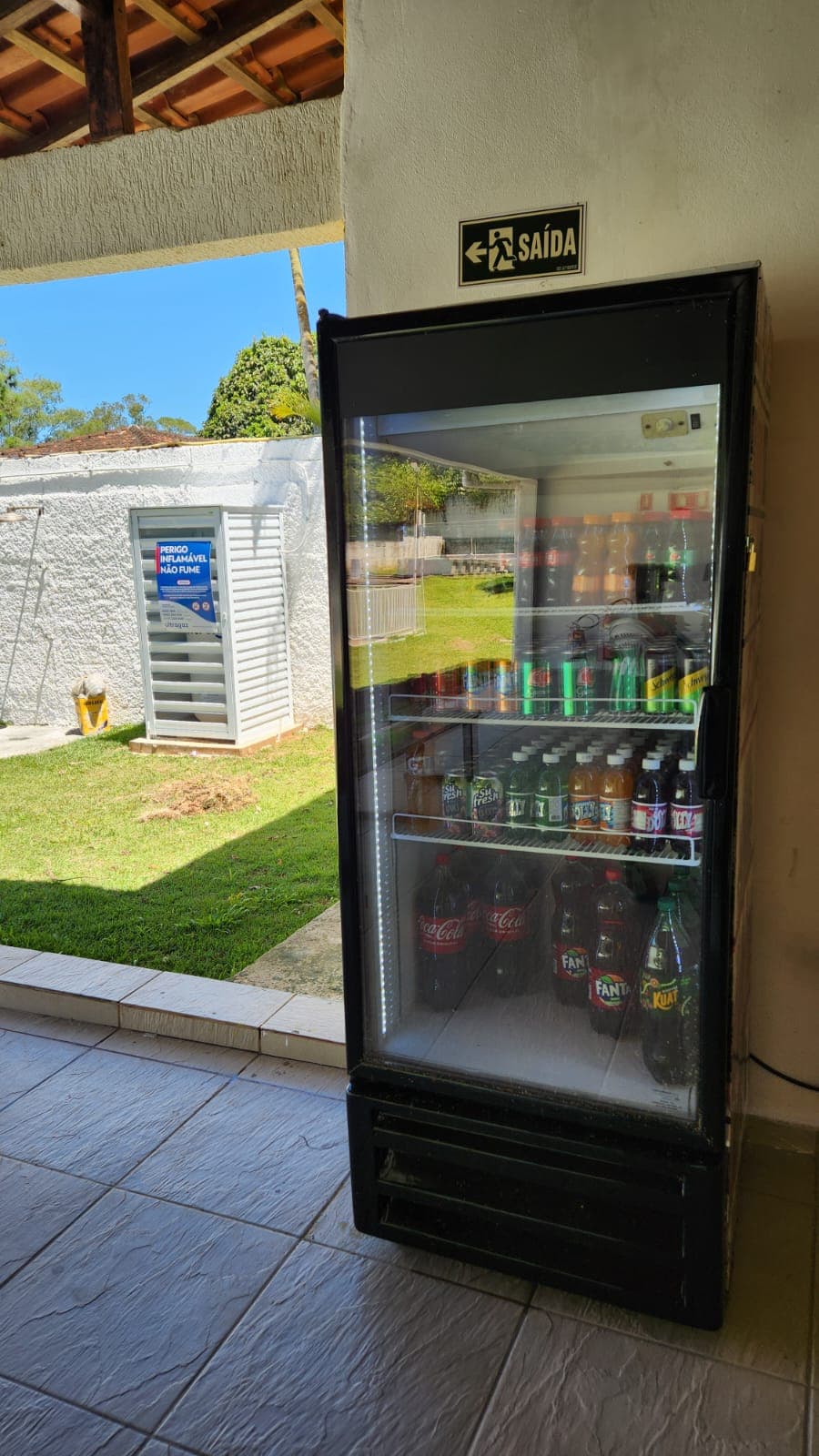 Refrigerador de bebidas em área coberta com vista para o jardim.