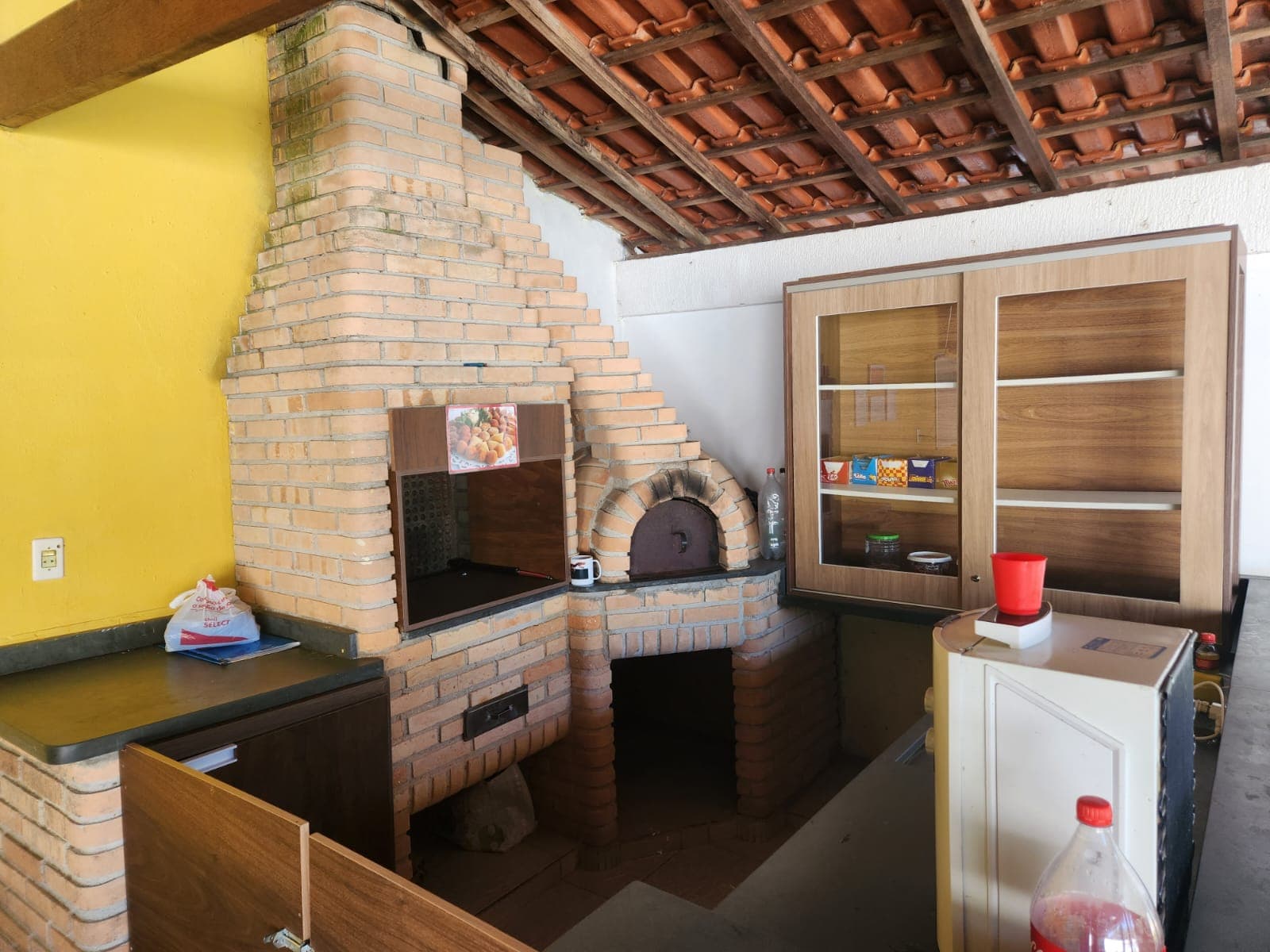 Área coberta com churrasqueira, forno e armário de apoio.