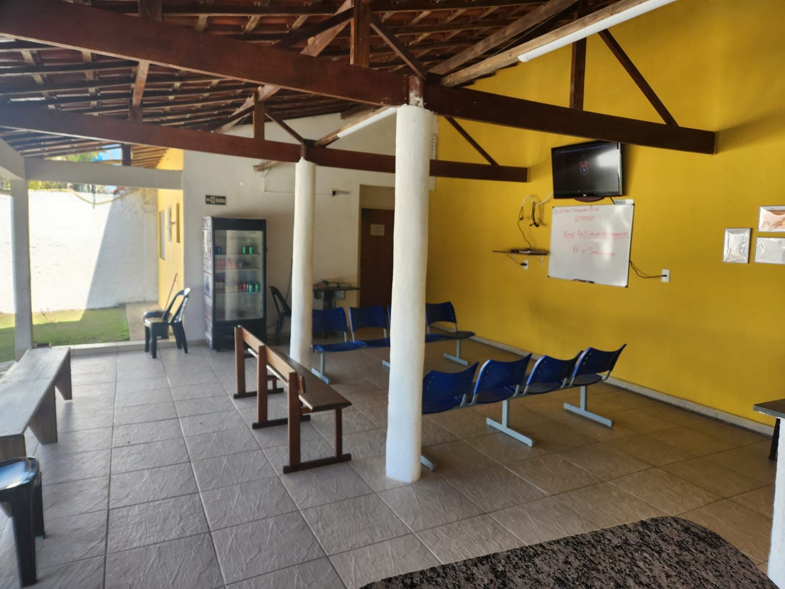 Espaço de convivência coberto com assentos e área aberta ao jardim.