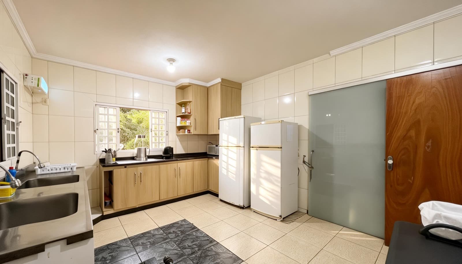 Cozinha com bancadas, pias, armários e refrigeradores.
