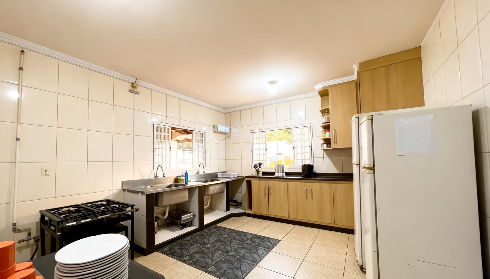 Cozinha com bancadas, pias, armários, fogão e refrigerador.
